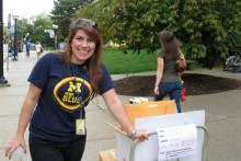 Michigan staff member with promotional materials on a roller cart